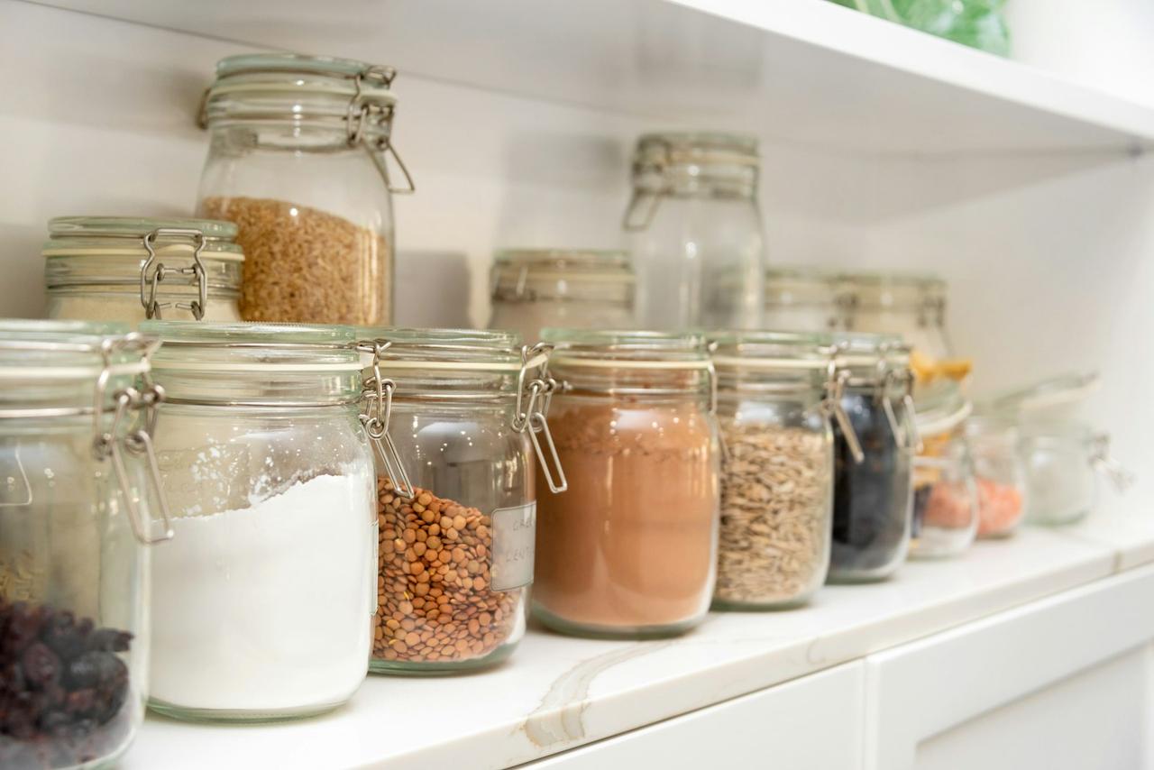plant-based pantry staples that save money — organized jars of beans and grains on wooden shelves
